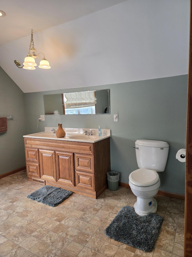 bathroom featuring toilet, vanity, an inviting chandelier, and vaulted ceiling