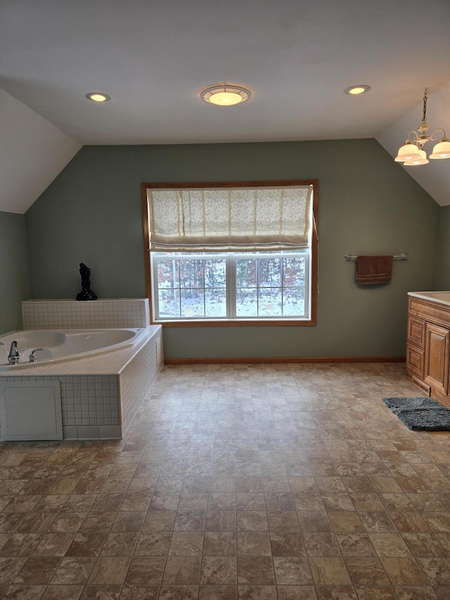 bathroom with vanity, vaulted ceiling, an inviting chandelier, and a relaxing tiled tub