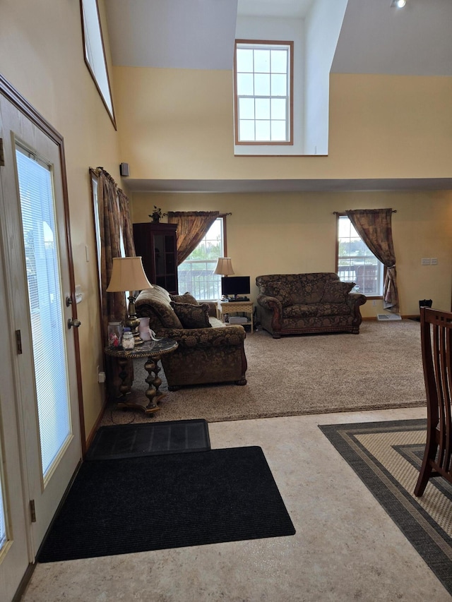 carpeted living room with a towering ceiling and plenty of natural light