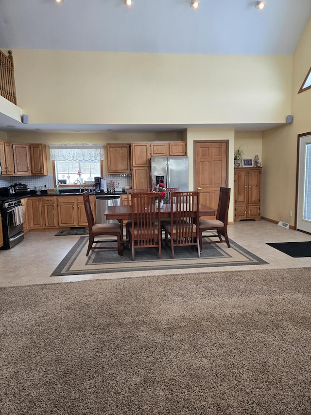 carpeted dining area featuring a high ceiling