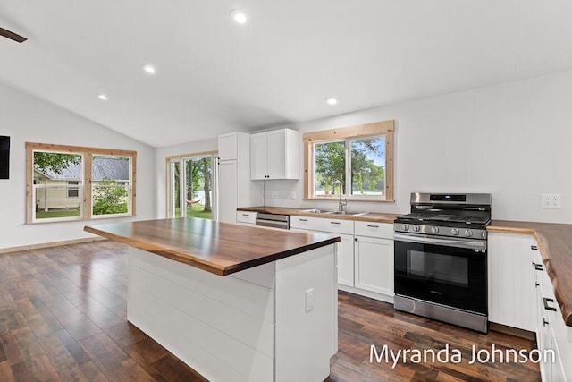 kitchen with stainless steel gas range oven, a wealth of natural light, sink, white cabinets, and wood counters