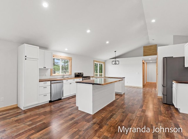 kitchen featuring lofted ceiling, decorative light fixtures, stainless steel appliances, and white cabinetry