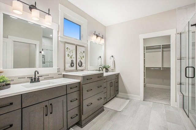 bathroom with a shower with door, backsplash, and vanity