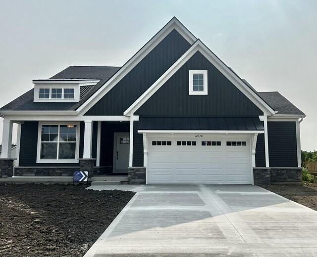 6970 Avalon Dr SE, Caledonia, MI 49316 - craftsman-style home with stone siding, concrete driveway, a standing seam roof, roof with shingles, and metal roof