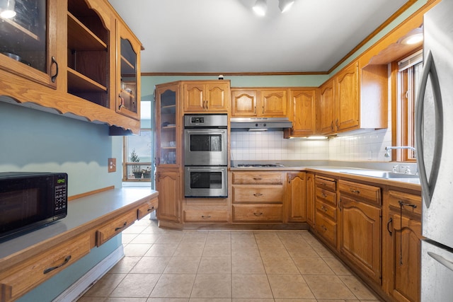 kitchen with appliances with stainless steel finishes, crown molding, light tile patterned floors, sink, and tasteful backsplash