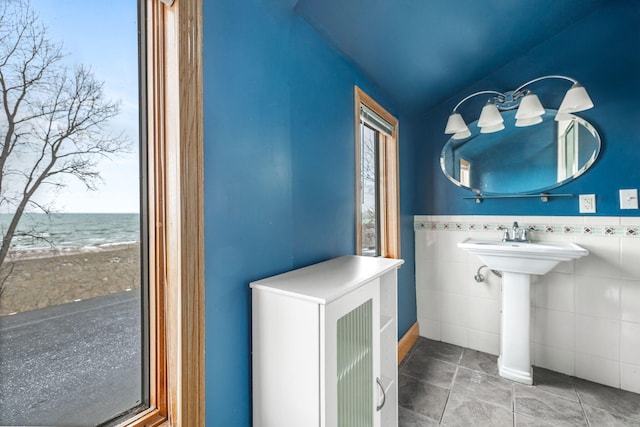 bathroom with tile walls, lofted ceiling, and a water view