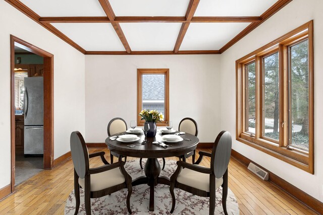 dining space featuring light hardwood / wood-style floors, coffered ceiling, and beamed ceiling