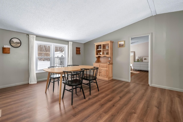 dining area featuring lofted ceiling, dark hardwood / wood-style flooring, and a textured ceiling