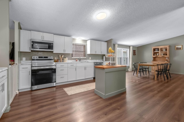 kitchen featuring lofted ceiling, sink, dark wood-type flooring, stainless steel appliances, and white cabinets