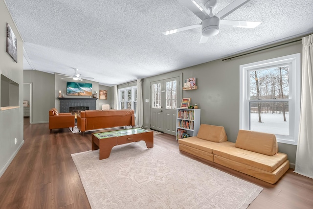 playroom with dark hardwood / wood-style floors, lofted ceiling, ceiling fan, a brick fireplace, and a textured ceiling