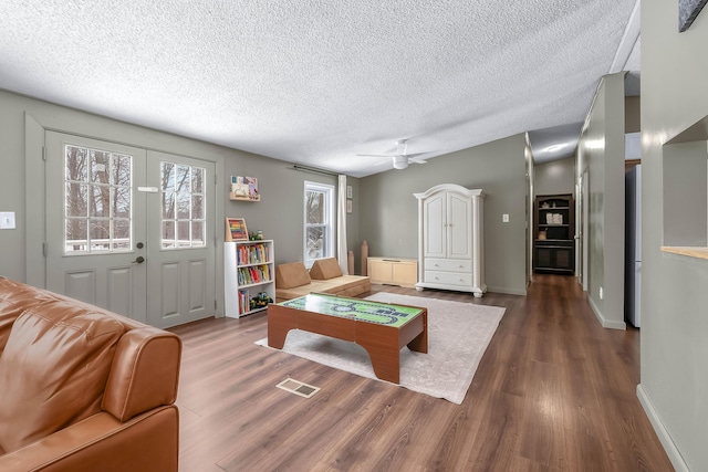 living room with ceiling fan, dark hardwood / wood-style floors, and a textured ceiling