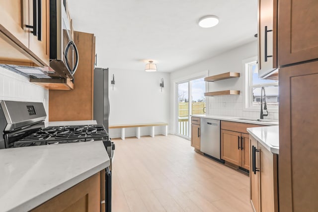 kitchen featuring appliances with stainless steel finishes, light hardwood / wood-style floors, decorative backsplash, and sink