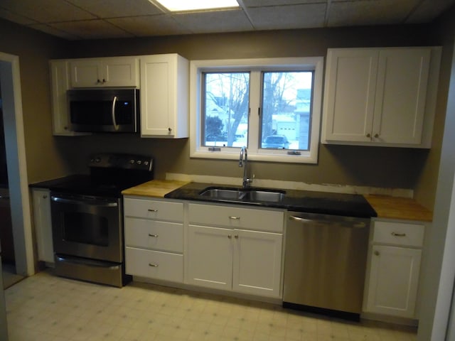 kitchen with sink, appliances with stainless steel finishes, a paneled ceiling, and white cabinetry