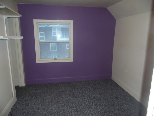 additional living space featuring lofted ceiling and dark carpet