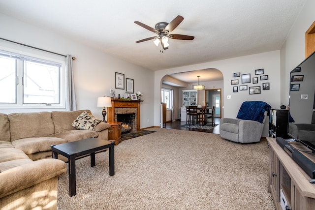 living room featuring ceiling fan, a brick fireplace, plenty of natural light, and carpet floors