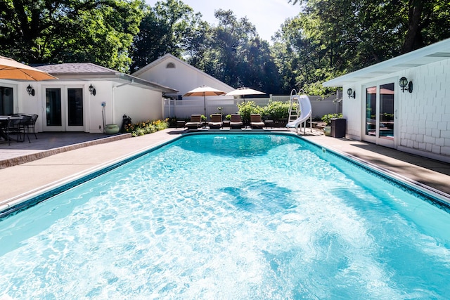 view of pool featuring a water slide, a patio, and french doors