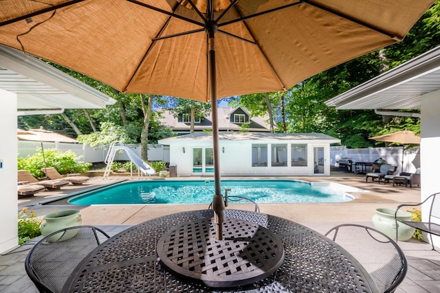 view of pool with a patio area, an outdoor structure, and a water slide