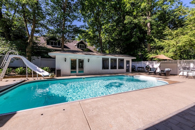 view of swimming pool featuring a water slide and a patio