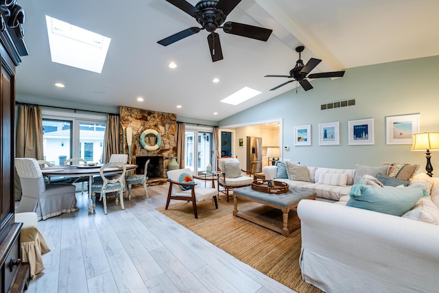 living room with ceiling fan, light wood-type flooring, vaulted ceiling, and a fireplace