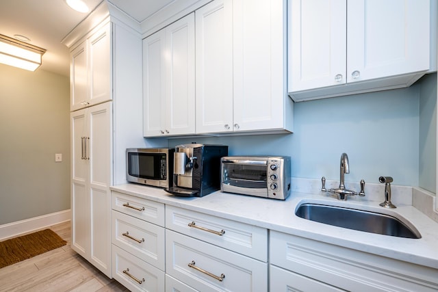 kitchen with sink, white cabinets, and light stone counters