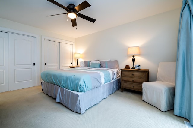 carpeted bedroom featuring ceiling fan and multiple closets