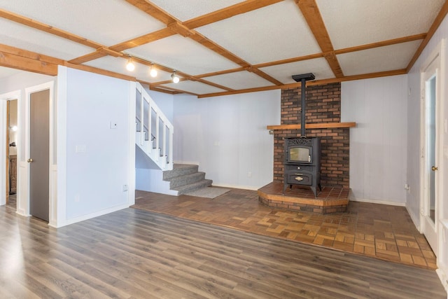 unfurnished living room featuring a textured ceiling, a wood stove, and coffered ceiling