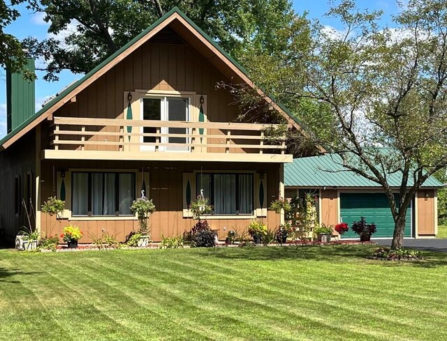 rear view of house with a garage, a lawn, and a balcony