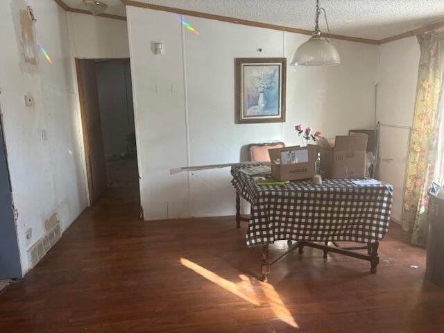 dining room with dark wood-type flooring, a textured ceiling, and crown molding