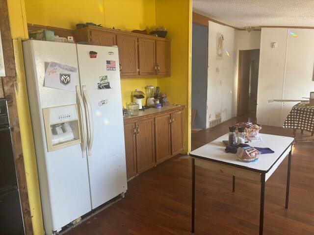 kitchen featuring dark hardwood / wood-style flooring, a textured ceiling, and white refrigerator with ice dispenser