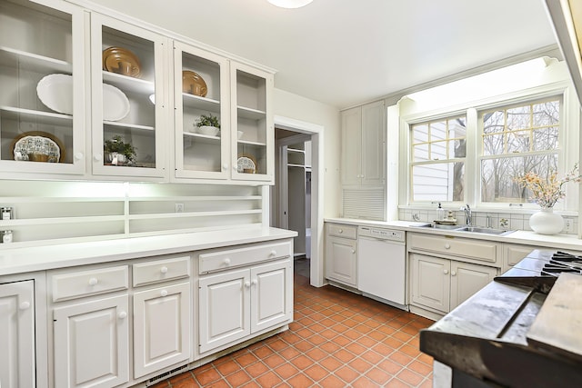 kitchen featuring dark tile patterned floors, white dishwasher, sink, and white cabinets