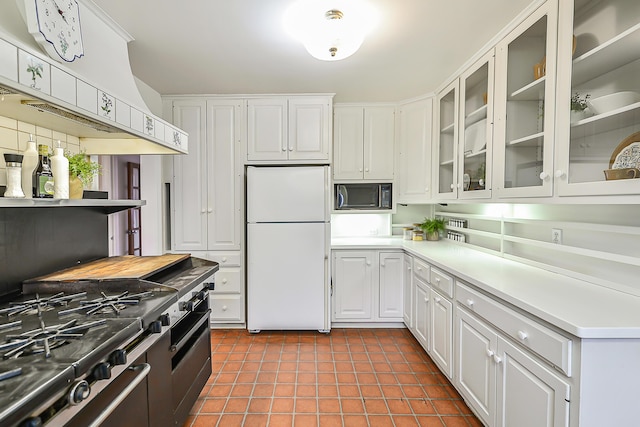 kitchen with white cabinetry, dark tile patterned floors, white fridge, and black microwave