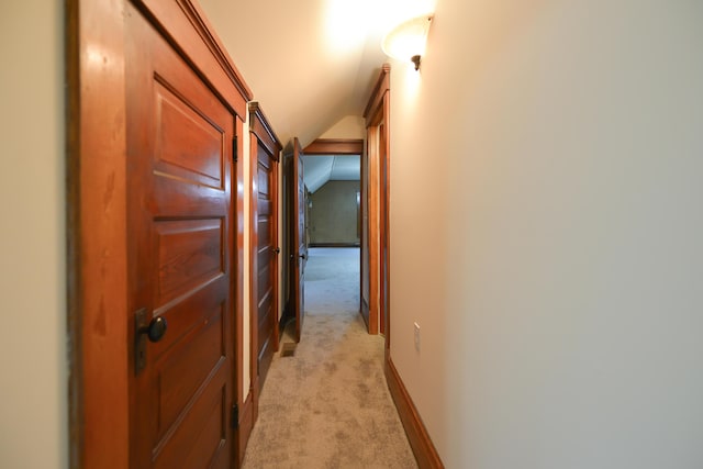 corridor featuring light carpet and vaulted ceiling