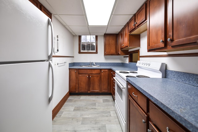 kitchen with white appliances, light hardwood / wood-style floors, sink, and a drop ceiling