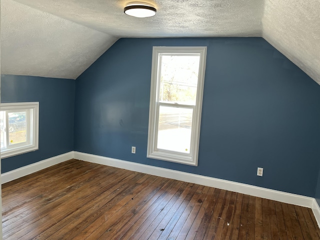 additional living space featuring hardwood / wood-style flooring, a textured ceiling, and vaulted ceiling