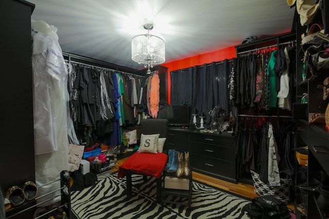 spacious closet with wood-type flooring and a notable chandelier