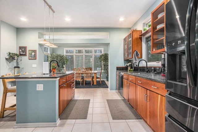 kitchen with pendant lighting, refrigerator with ice dispenser, a kitchen breakfast bar, sink, and a kitchen island with sink