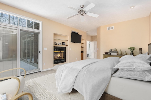 carpeted bedroom featuring ceiling fan, access to exterior, and a tiled fireplace