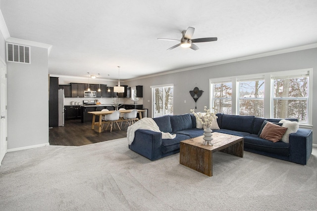 carpeted living room with ceiling fan and ornamental molding