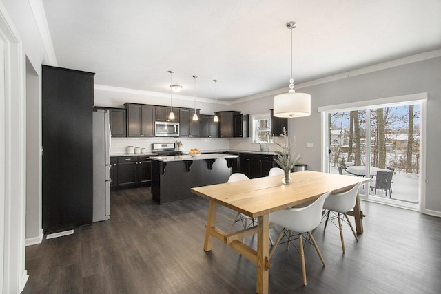 dining space with sink, ornamental molding, and dark wood-type flooring