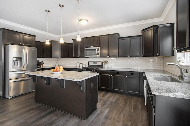 kitchen with stainless steel appliances, pendant lighting, a kitchen bar, a kitchen island, and sink