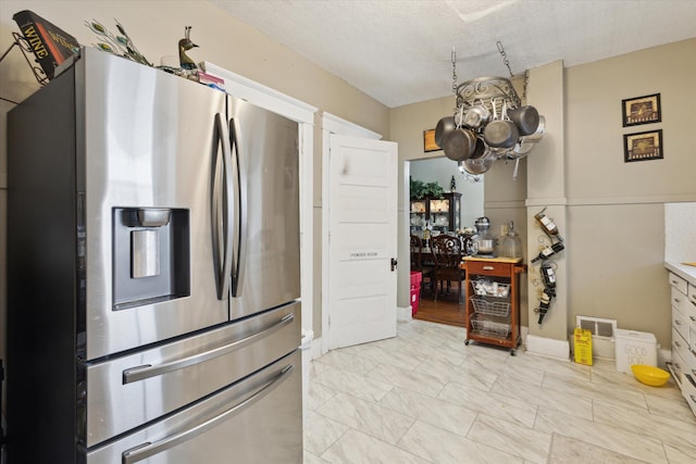 kitchen featuring stainless steel fridge, an inviting chandelier, and a textured ceiling