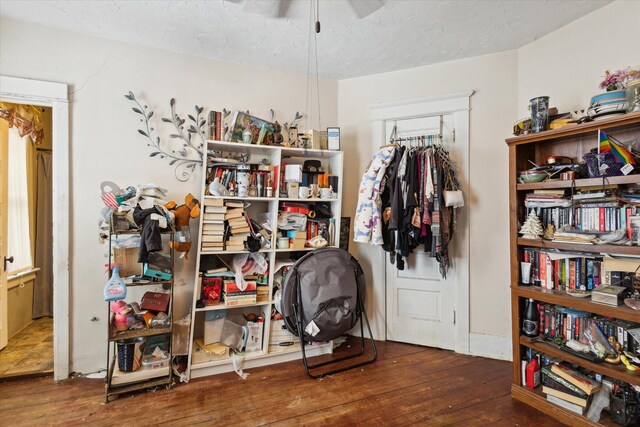 miscellaneous room featuring ceiling fan, dark wood-type flooring, and a textured ceiling