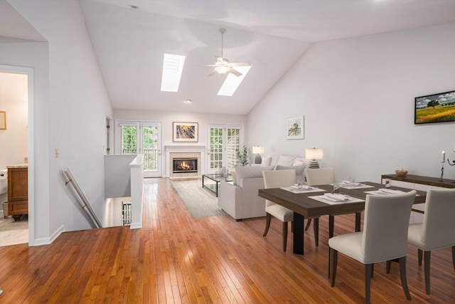 dining room featuring vaulted ceiling with skylight, ceiling fan, and light hardwood / wood-style flooring