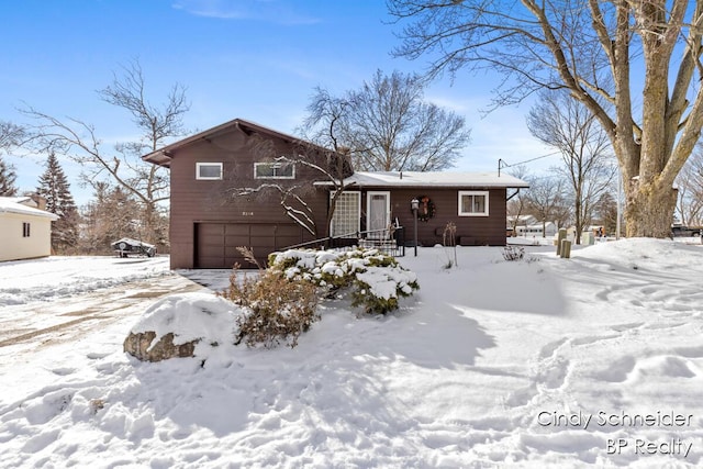 snow covered back of property with a garage