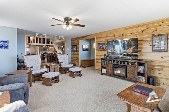 living room with ceiling fan, light colored carpet, and wooden walls