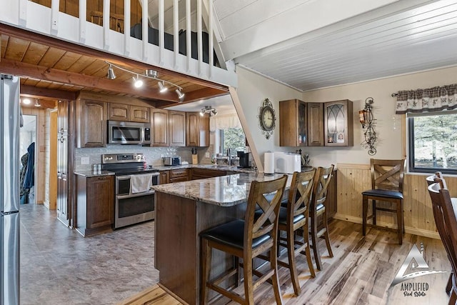 kitchen with stainless steel appliances, dark stone countertops, plenty of natural light, a kitchen breakfast bar, and kitchen peninsula