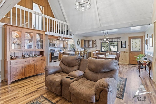 living room with high vaulted ceiling, light wood-type flooring, wooden walls, and a chandelier