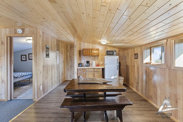 dining space with lofted ceiling, wood walls, and wooden ceiling