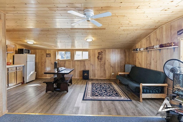 living room with hardwood / wood-style floors, wooden walls, wooden ceiling, ceiling fan, and vaulted ceiling