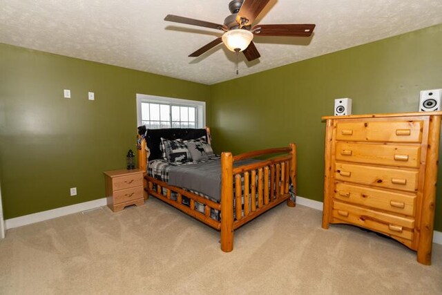 bedroom featuring ceiling fan, light colored carpet, and a textured ceiling